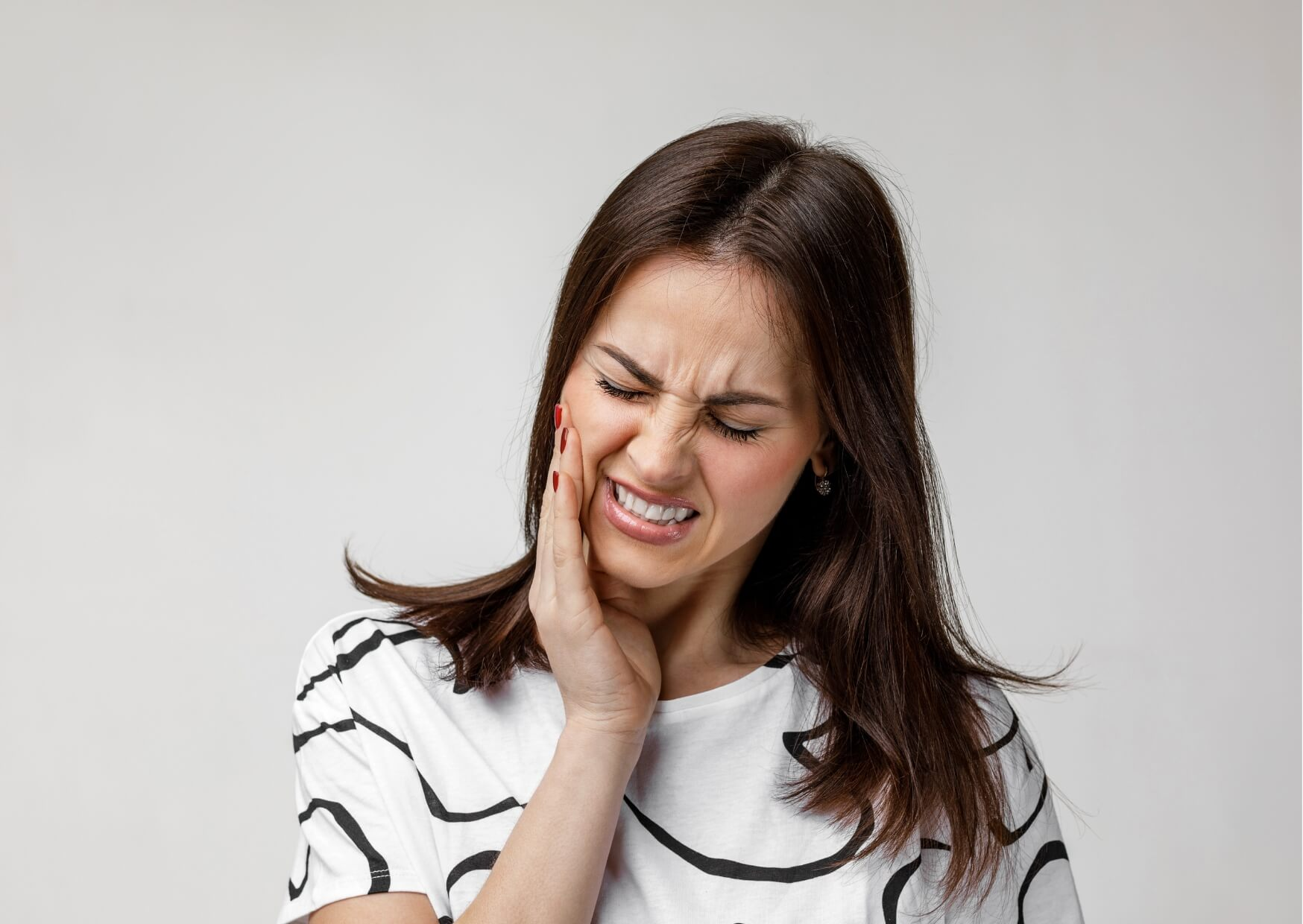 Person holding their jaw in pain, illustrating what a cracked tooth feels like with sharp tooth sensitivity and discomfort.