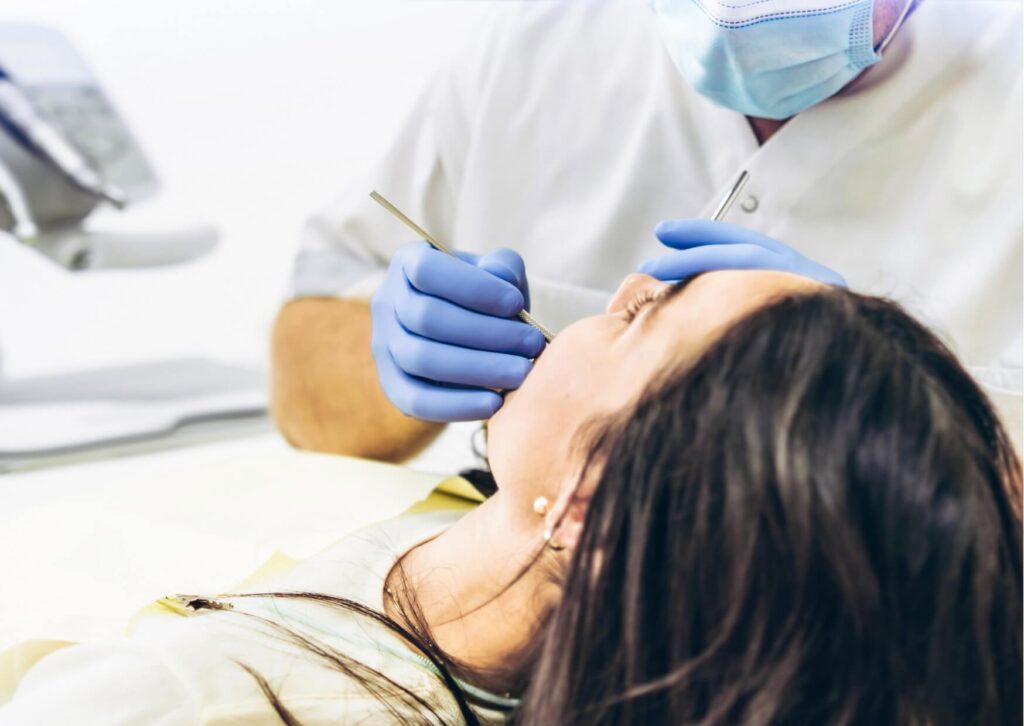 Dentist examining a patient's mouth to evaluate a wisdom tooth coming in and check for signs of impaction or crowding.