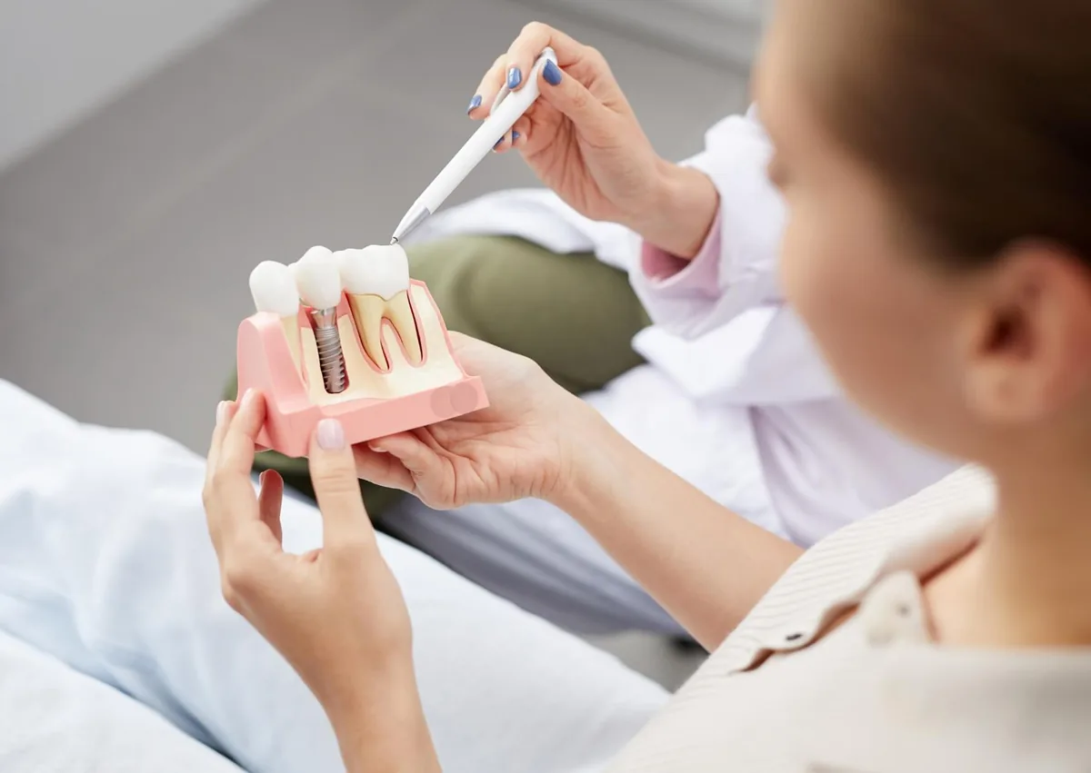 Dental professional using a tooth model to explain the implant process and how long a tooth implant can take.