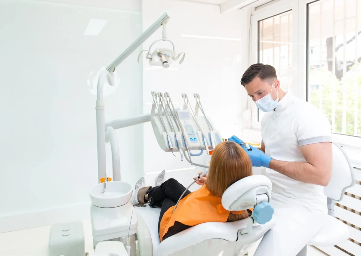 Dentist performing a dental procedure on a patient, illustrating the teeth bonding treatment process.