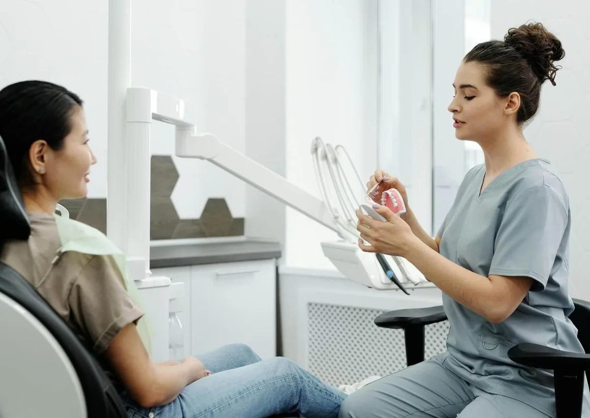 Dental professional using a tooth model to explain what cavities can look like and how tooth decay develops.