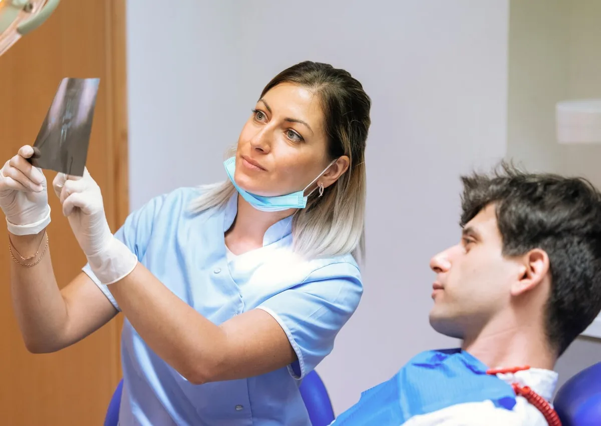 Dental professional reviewing an X-ray with a patient while discussing affordable dental implant treatment options.