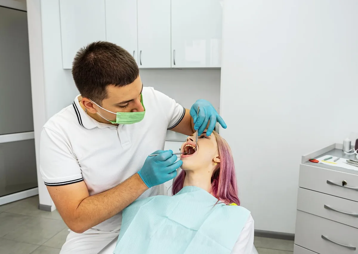 Dentist examining a patient’s teeth and gums to evaluate options for gummy smile treatment.