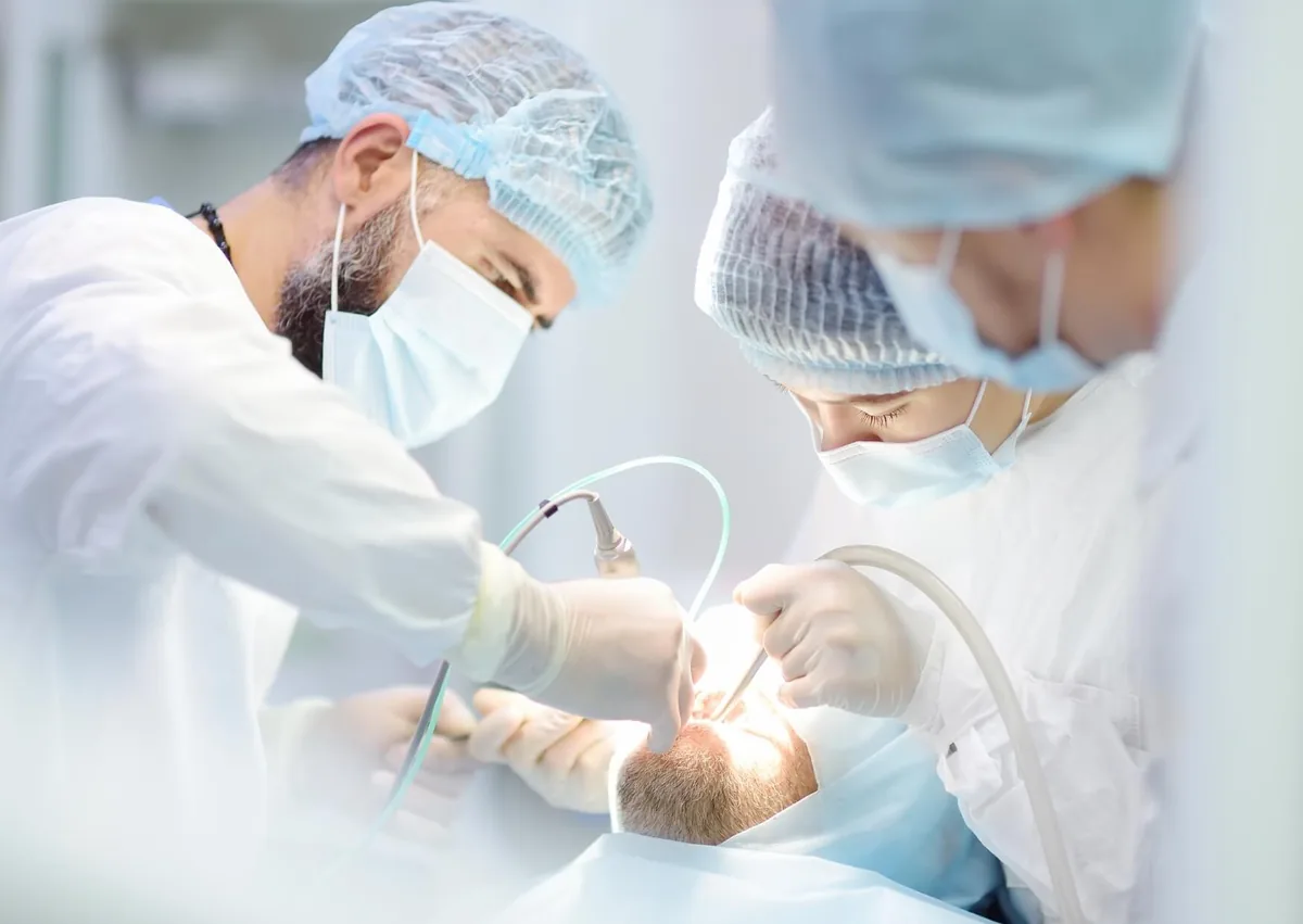 Dental team performing implant surgery while the patient receives sedation for comfort.